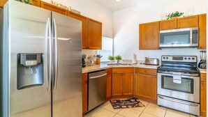 A modern kitchen with stainless steel appliances, wooden cabinets, and a built-in microwave. - 3 Minutes to Disney — Windsor Palms Single Level home w Private Pool, Game Room, & Expansive Patio (Kissimmee)