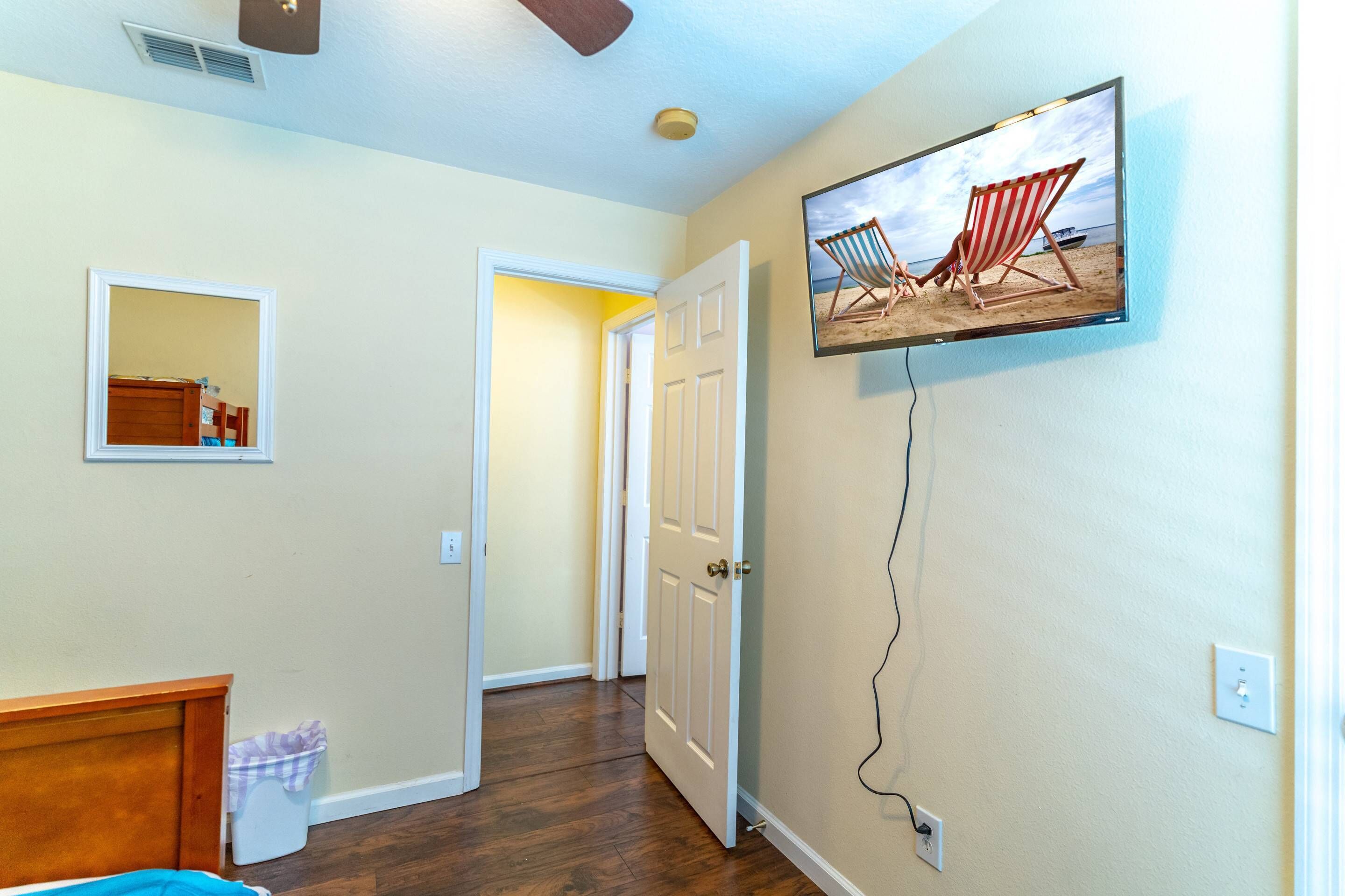 A room with a bed, a television mounted on the wall, and a door leading to another room.