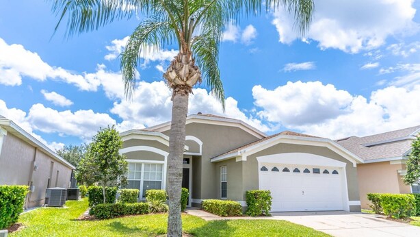 A single-story house with a garage, surrounded by well-maintained lawns and a palm tree. - 3 Minutes to Disney — Windsor Palms Single Level home w Private Pool, Game Room, & Expansive Patio (Kissimmee)