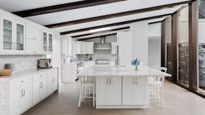 A modern kitchen with white cabinetry, a large island, and a stone wall view.