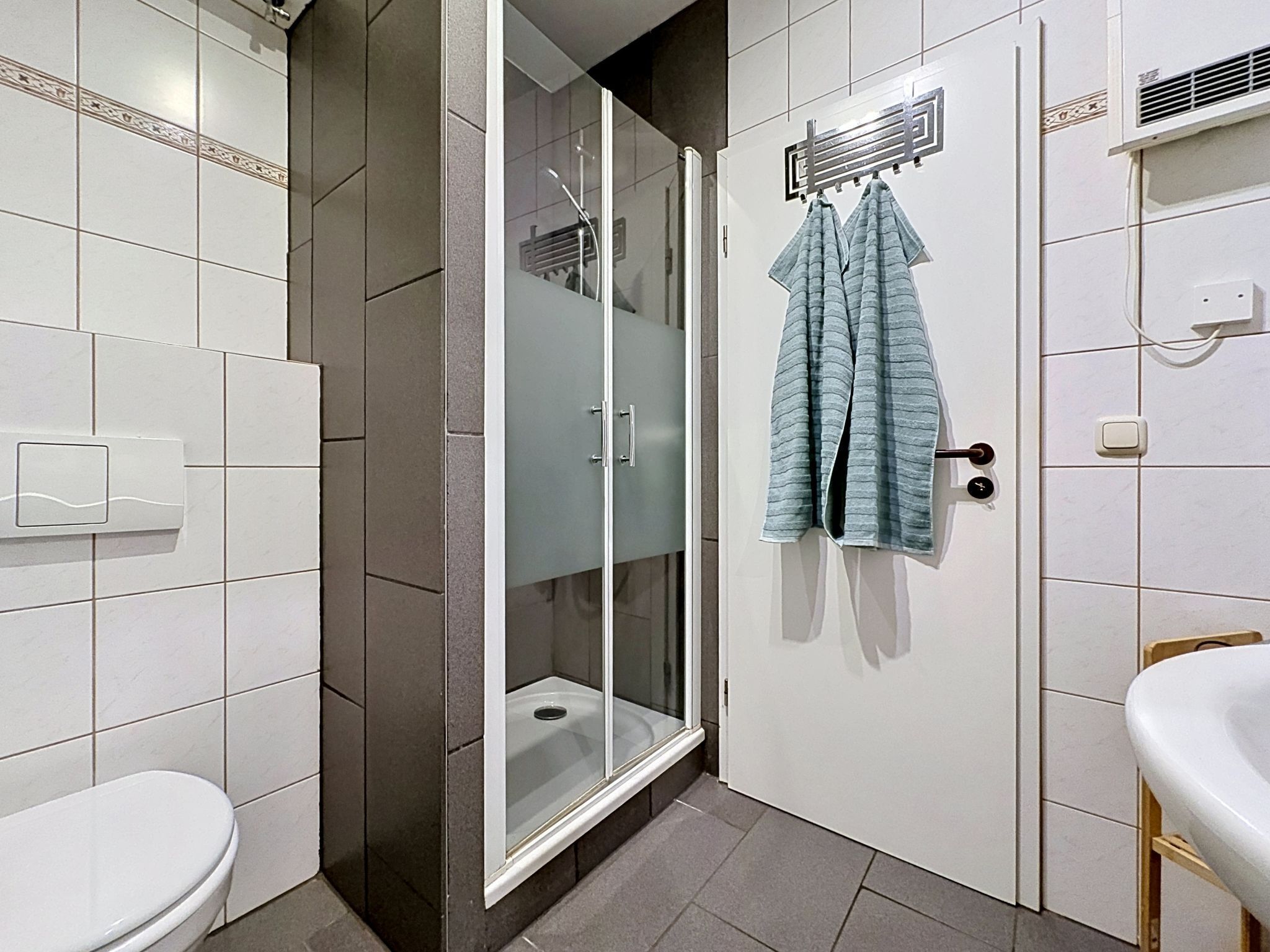 A bathroom with a toilet, a shower with glass doors, and a sink.