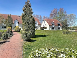 A row of white houses with red roofs, a paved pathway, and a well-maintained lawn.