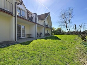 A two-story house with a covered patio, a balcony, and a grassy yard.
