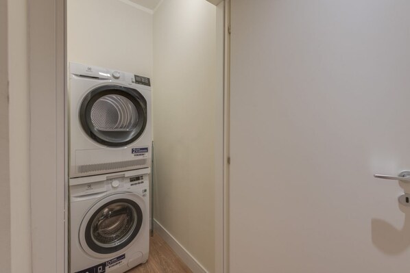 A laundry room with two stacked washing machines and a door.