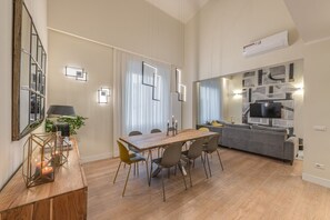 A modern living room with a dining table, sofas, and a TV.