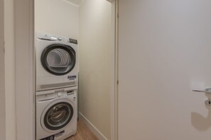 Une buanderie avec deux machines à laver superposées et une porte.
