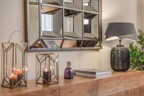 A wooden console table with a mirror, a lamp, candles, and books. - Luxury 4-bedroom, 4-bathroom apartment. (Firenze)