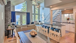 A spacious living area with a dining table, sofa, and kitchen in the background. - Lake Pend Oreille Home w/ Dock & Paddle Boards (Sagle)