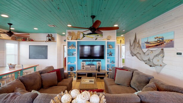 A living room with a large flat-screen TV, wooden ceiling, and a nautical-themed wall decoration. - OV23 Shared Pool, Pet Friendly, Golf Cart Access (Port Aransas)