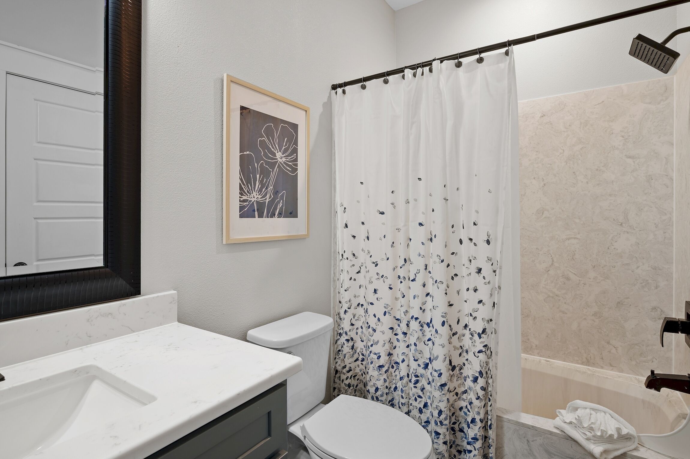 A bathroom with a white sink, toilet, and shower area.