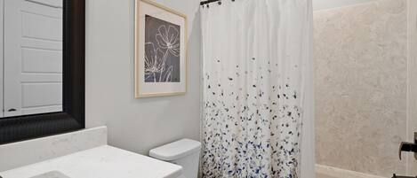 A bathroom with a white sink, toilet, and shower area.