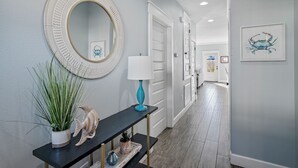 A hallway with a round mirror, a blue lamp, and a fish sculpture on a console table. - Private Pool ~ Golf Cart ~ Walk to the Beach (Miramar Beach)