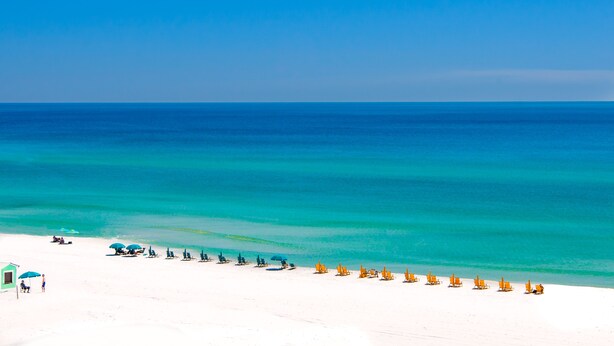 A beach with rows of sun loungers and umbrellas, a lifeguard tower, and a clear view of the ocean. - Private Pool ~ Golf Cart ~ Walk to the Beach (Miramar Beach)