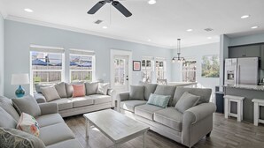 A spacious living room with a grey sofa set, a coffee table, and a ceiling fan. - Private Pool ~ Golf Cart ~ Walk to the Beach (Miramar Beach)