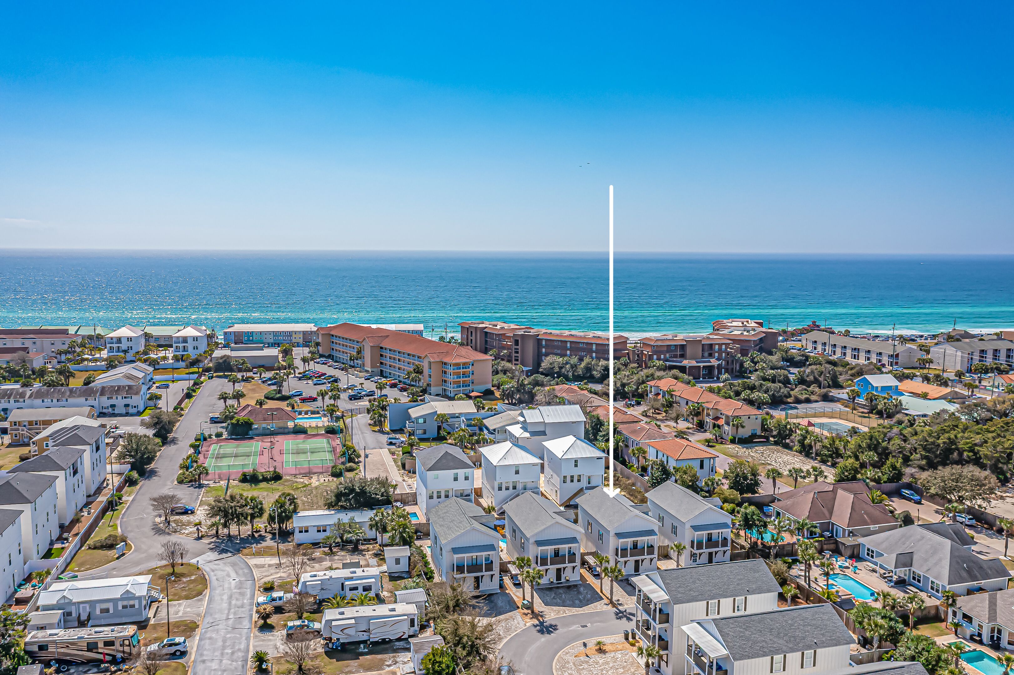 A coastal residential area with houses, a road, and a view of the ocean.