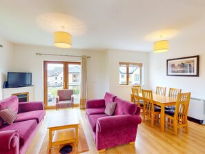 Relax in this stylish living room with a large window, flat-screen TV, and dining area.