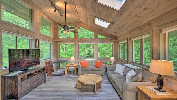 A spacious living room with a wooden ceiling, large windows, and a ceiling fan. - House w/ Balcony ~ 5 Mi to Cranmore Resort! (Bartlett)