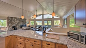 A spacious kitchen with granite countertops, a stone fireplace, and a large island. - House w/ Balcony ~ 5 Mi to Cranmore Resort! (Bartlett)