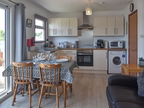 Cocina compacta con comedor, que incluye una mesa puesta para cuatro, sillas, lavadora y microondas.