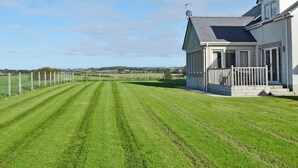 Una casa con un grande prato, un'antenna parabolica e un'area recintata.