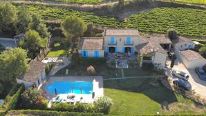 A villa with a swimming pool, surrounded by lush vineyards.