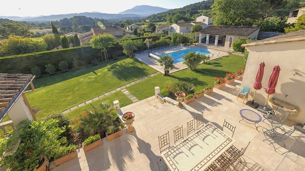 A residential property with a swimming pool, outdoor seating, and a view of the surrounding landscape.