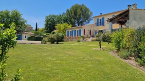 A well-maintained garden with a lawn, a pathway, and a building with a tiled roof and blue shutters.