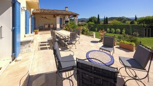 An outdoor patio with a table and chairs, a pergola, and a view of the countryside.