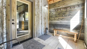 A rustic wooden interior with a large glass door, a bench, and a coat rack.