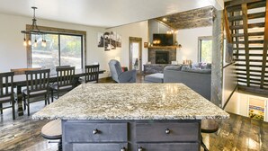A kitchen with a granite countertop, wooden cabinets, and a dining area with a table and chairs.
