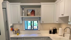 A kitchen with white cabinetry, a window with a view, a sink, and a countertop with various items. - Modern rustic condo in the heart of iconic Sun Valley (Sun Valley)