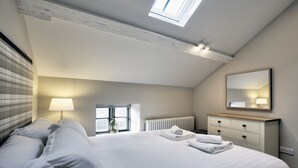 Ein Schlafzimmer mit Bett, Fenster, Heizkörper, Schminktisch und Spiegel.