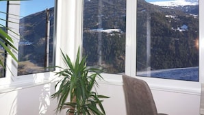 A room with a large window offering a view of snow-capped mountains and a forested valley. - Apartment Gabi by Interhome (Wenns)