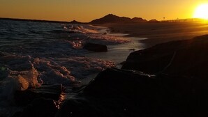Un atardecer sobre una costa rocosa con olas rompiendo en la orilla.