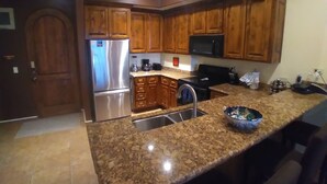 Una cocina con armarios de madera, electrodomésticos de acero inoxidable, encimeras de granito y microondas integrado.