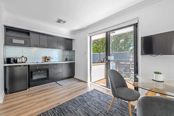 A modern kitchen with a built-in oven, a dishwasher, and a large window overlooking a balcony.