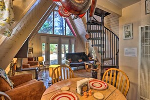 Enjoy a spacious loft-style living space with a dining area, spiral staircase, and large windows offering a view of the outdoors.