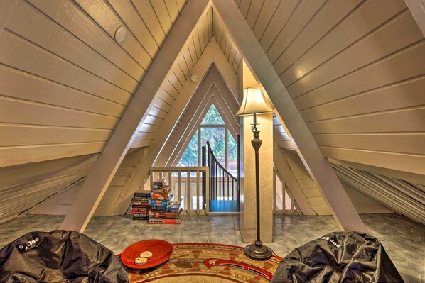 Cozy attic retreat with a large window offering a view of the outdoors and a collection of books on a shelf.