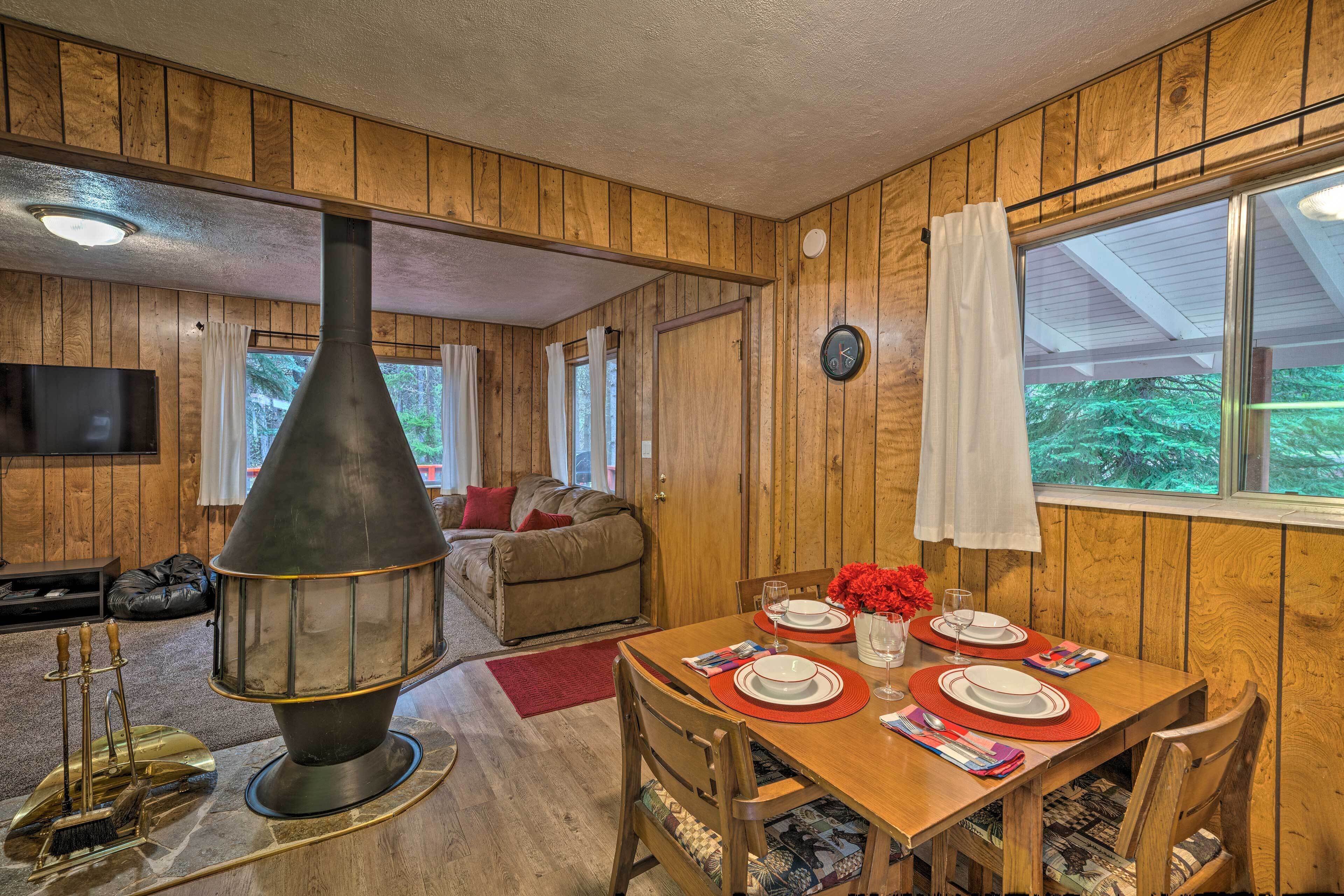 Un interior de madera con una mesa de comedor para cuatro personas, una chimenea y un televisor en la sala.