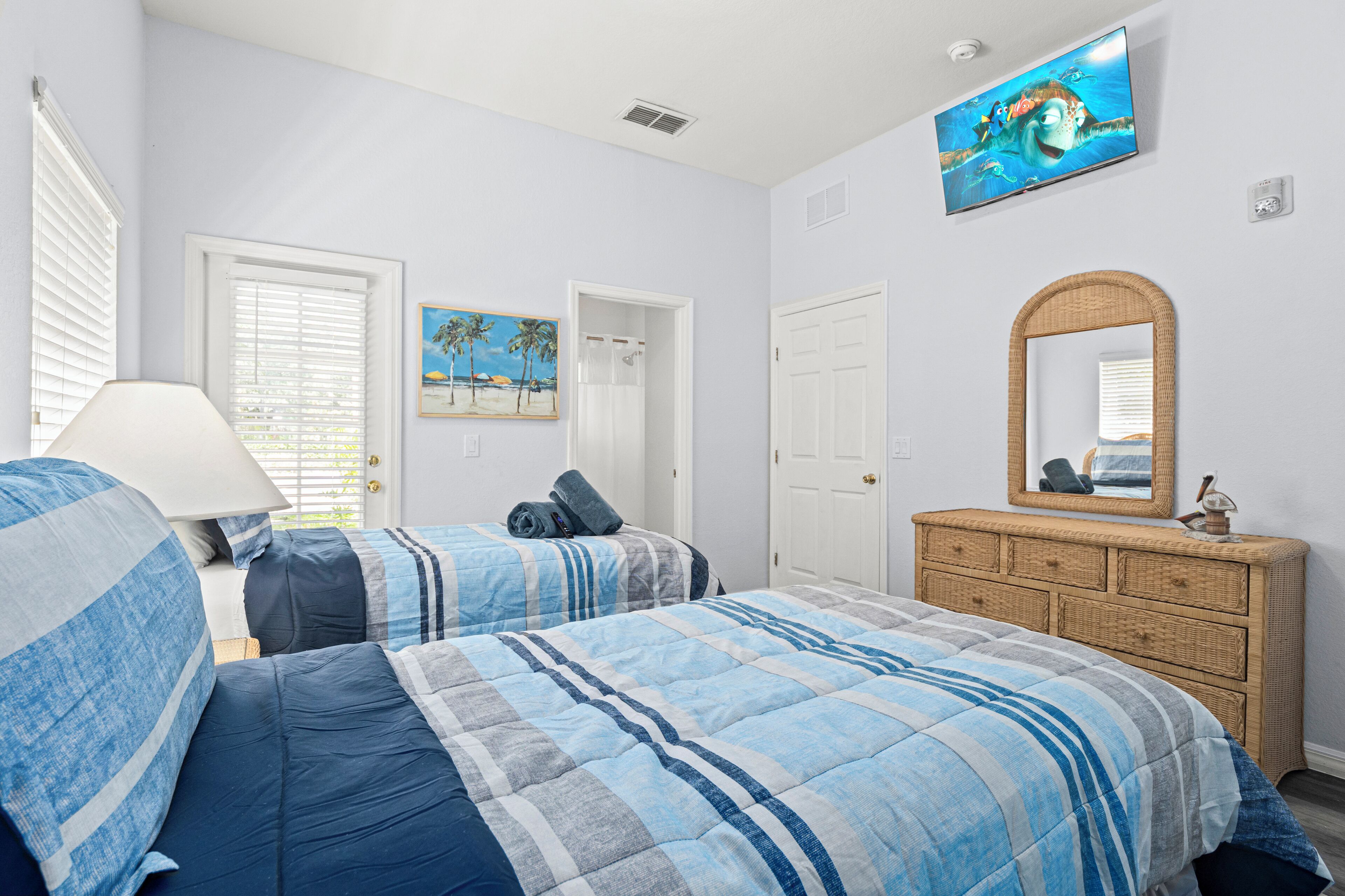 A bedroom with two beds, a dresser, a TV, and a painting.