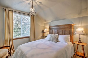 Camera da letto ordinata con un letto grande, due comodini con lampade, una testata del letto in legno e una finestra con tende.