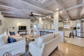 Relax in this inviting living area with a sofa set, coffee table, and TV, adjacent to a fully equipped kitchen.