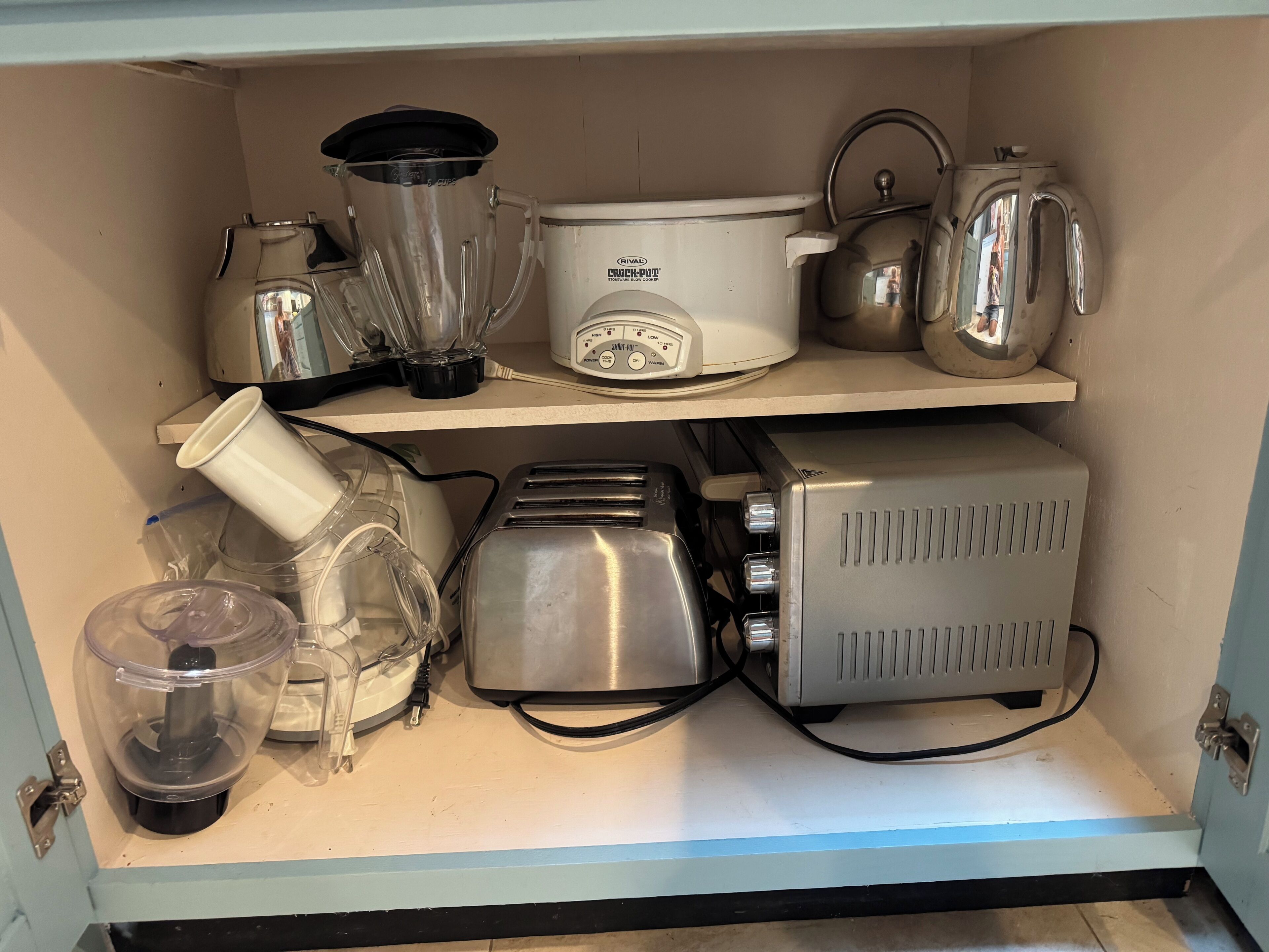 A kitchen with a blender, toaster, kettle, and a container.