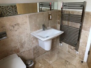 Un baño con lavamanos, espejo y toallero.