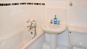 A bathroom with a bathtub, a pedestal sink, and a toilet. - Meadowside Apartment (Fowey)
