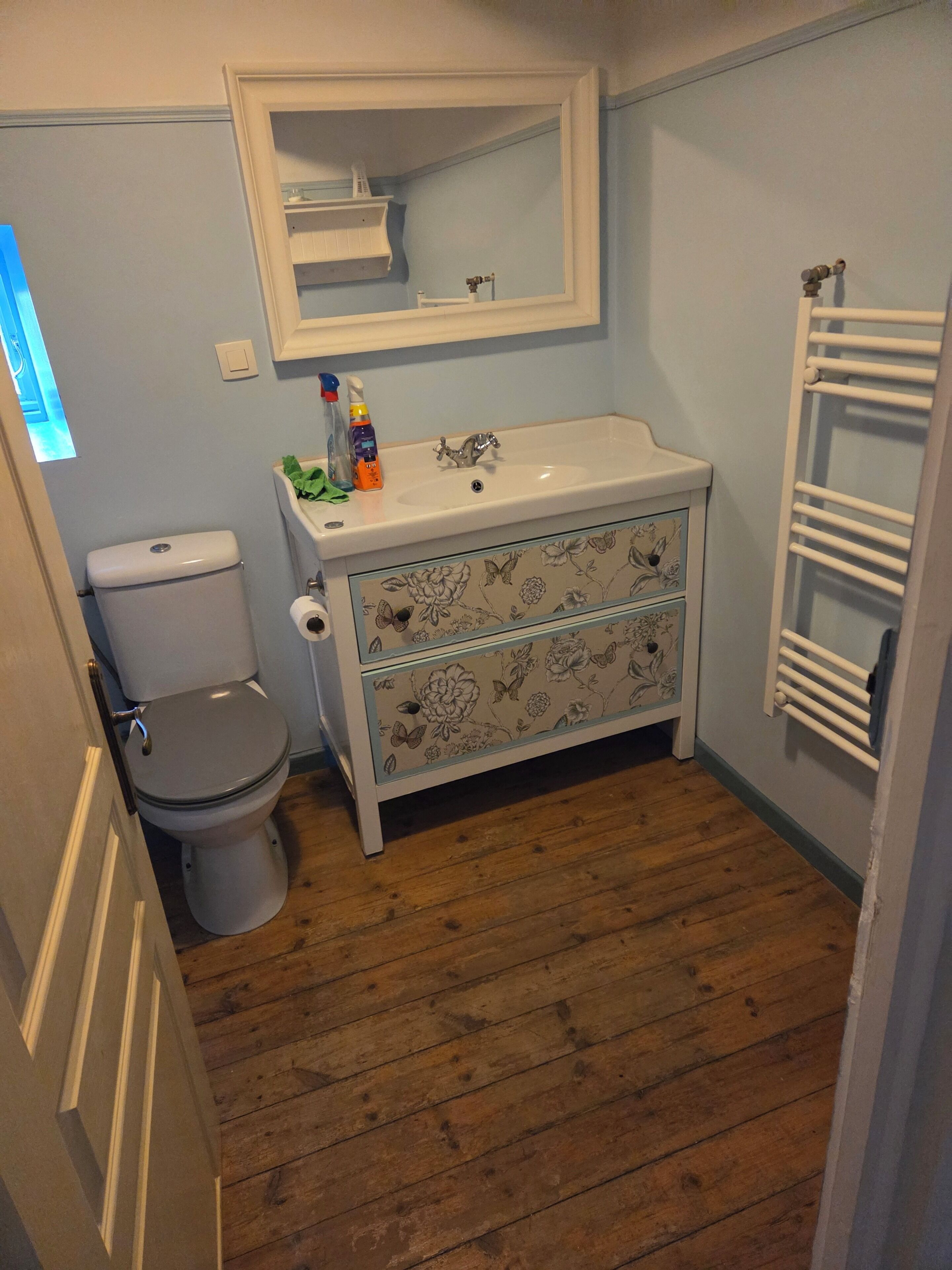 Une salle de bain équipée d’un WC, d’un lavabo, d’un miroir et d’un porte-serviettes.