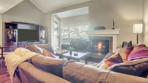 Una sala de estar con chimenea, sofá de cuero y televisor.