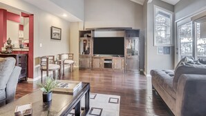 Una sala de estar amplia con un televisor grande, armarios de madera y un espacio de descanso cómodo.