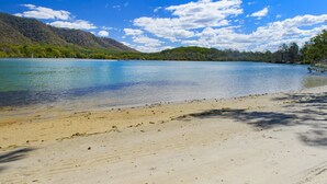 Una playa con aguas cristalinas y un promontorio boscoso al fondo.