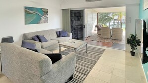 Una sala moderna con un sofá gris, una mesita de centro y un ventanal con vistas al exterior.